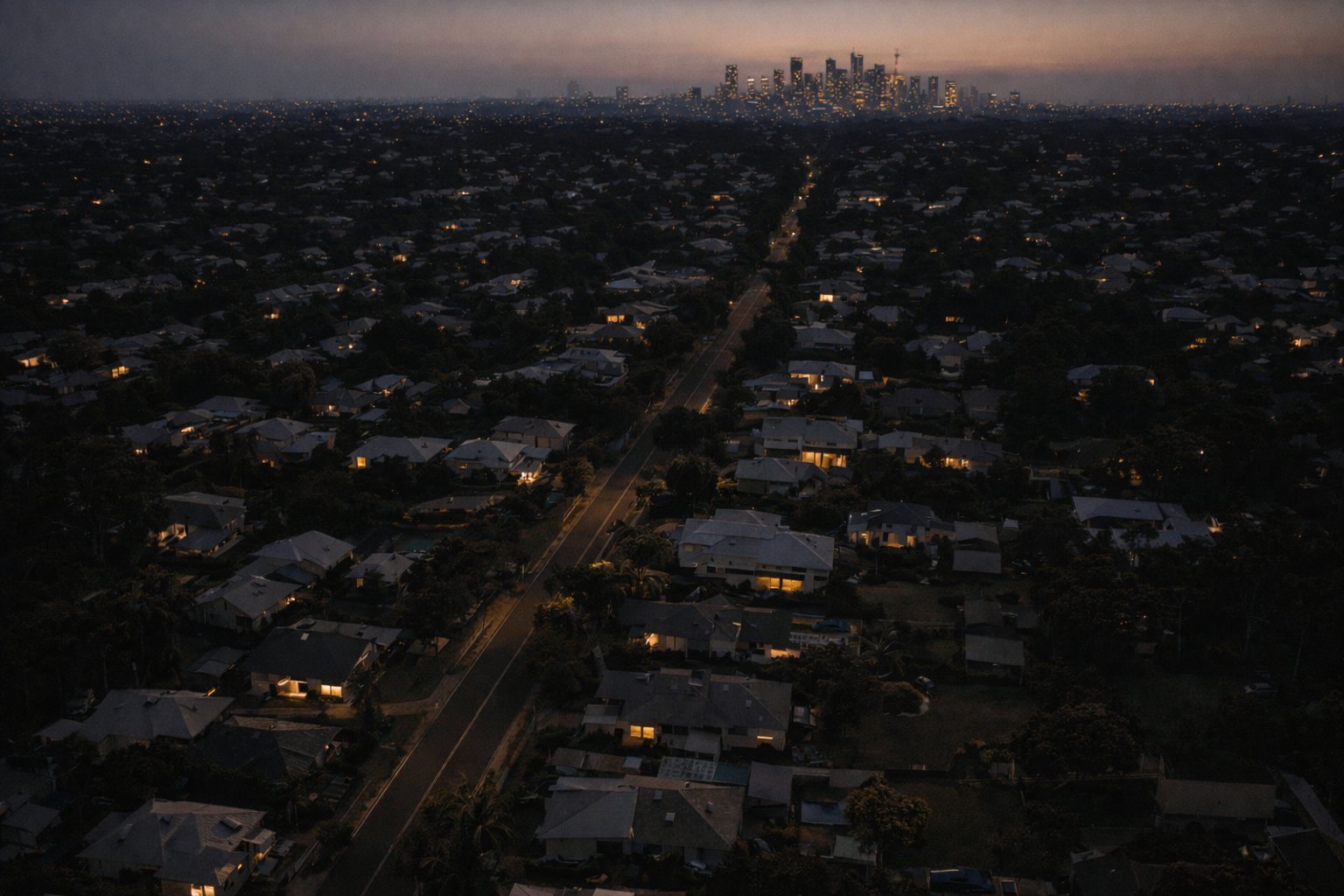 Aerial view at twilight of an established residential suburb with a distant city skyline on the horizon
